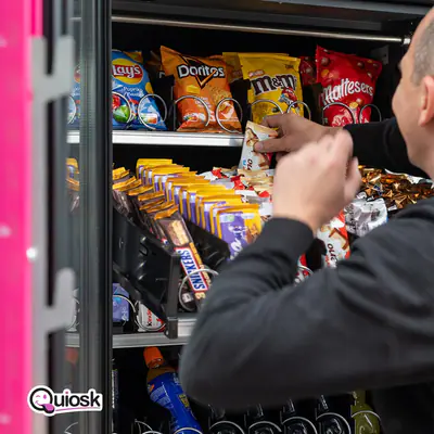 Een collega vult de schappen van een Quiosk bij