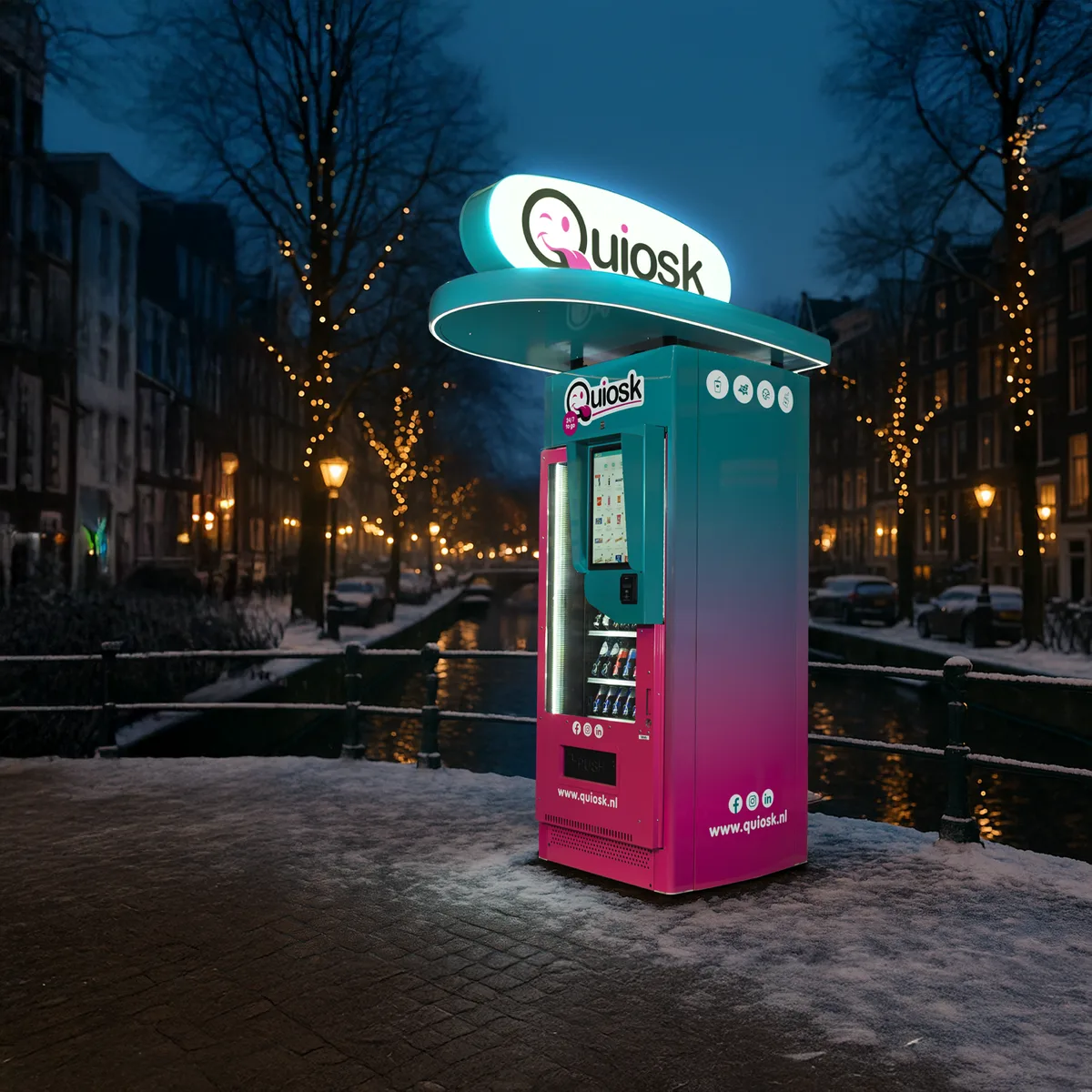Een Quiosk-automaat in de avond langs een besneeuwde gracht, met het logo verlicht.